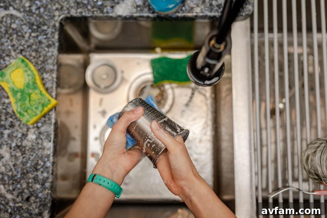 A person kneeling to repair a pipe under a sink using a hand wrench